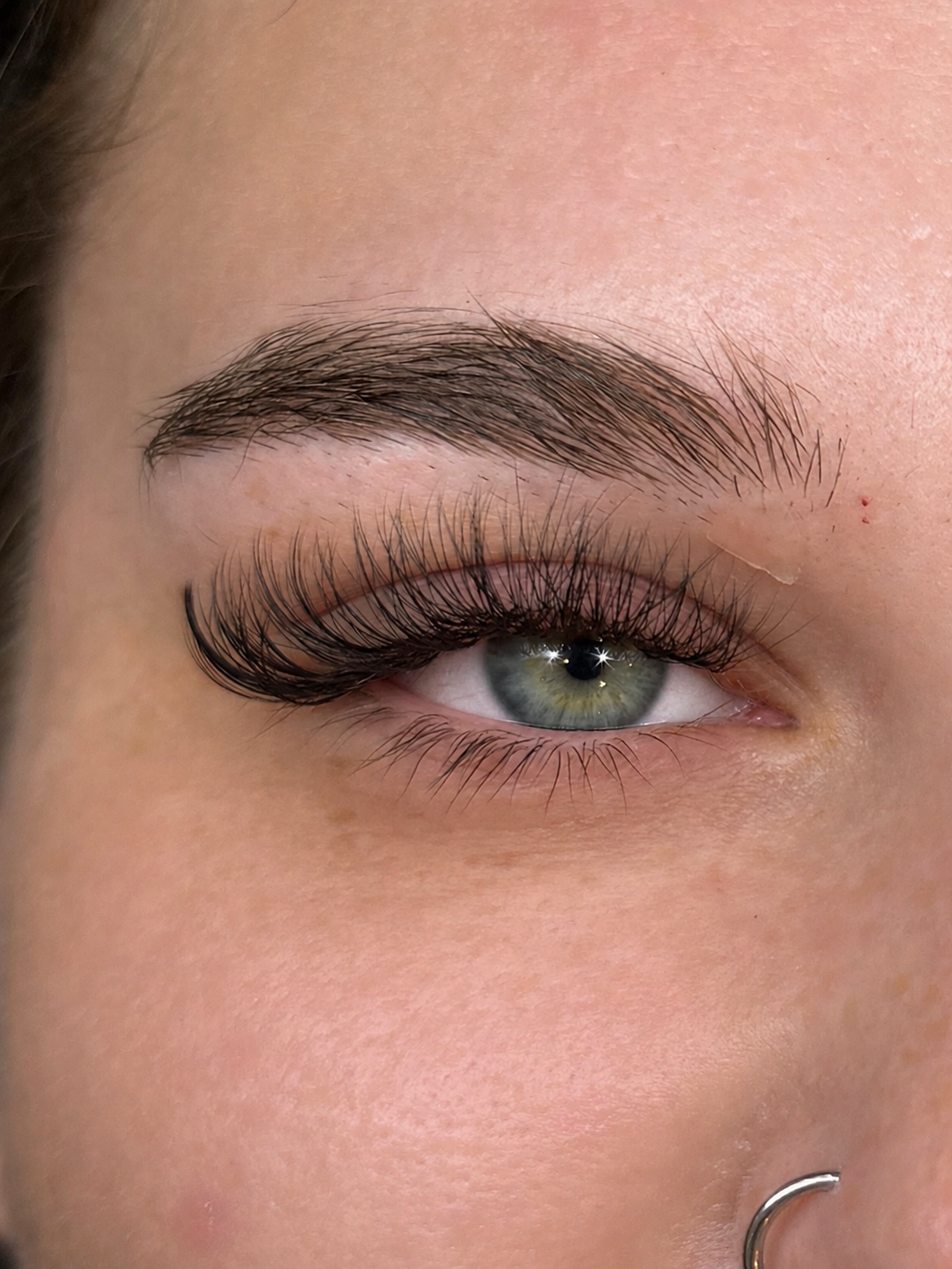 Medium volume lash extension set, close-up of a green eye
