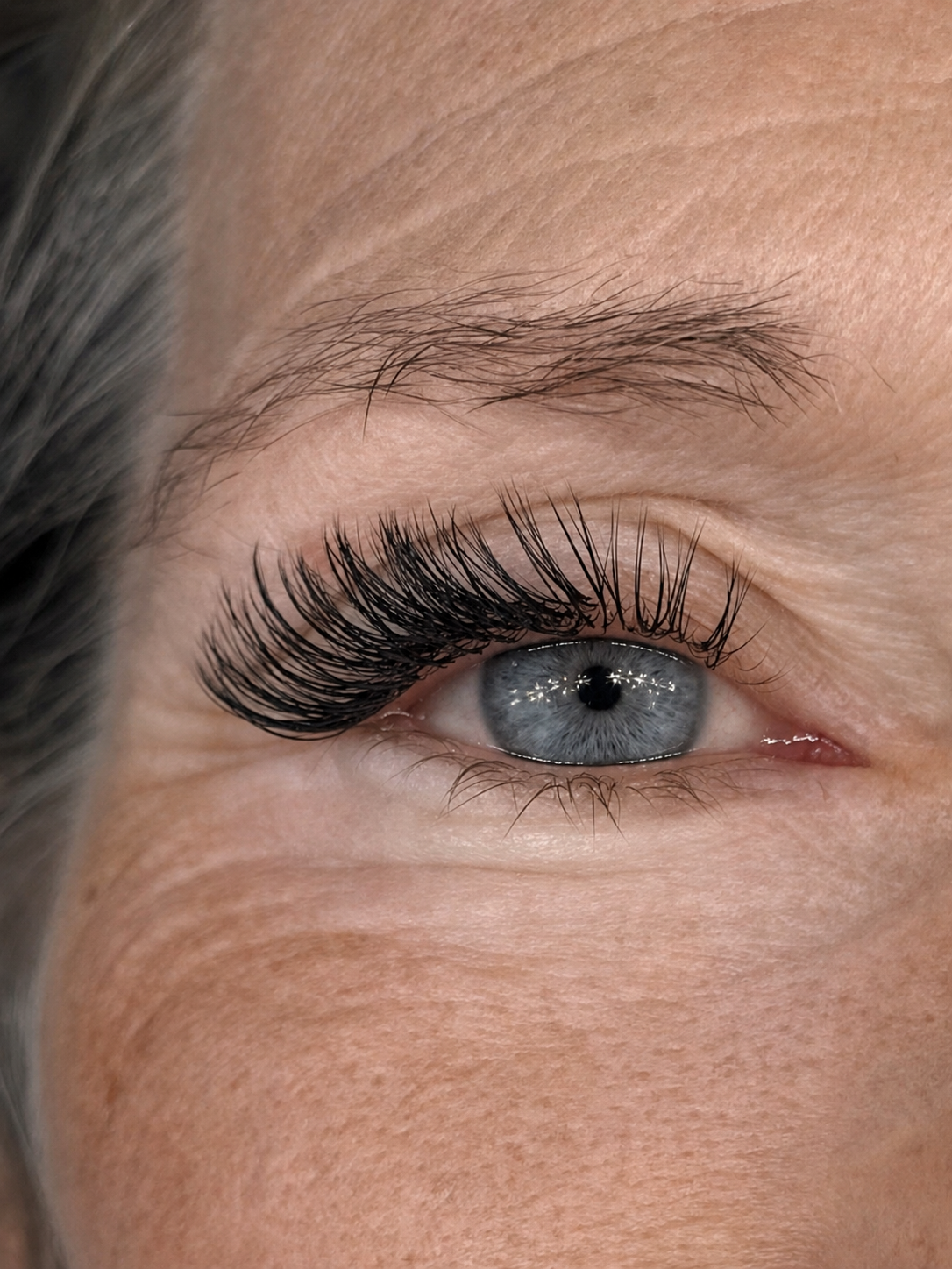 Medium lash extension set, close-up of a blue eye